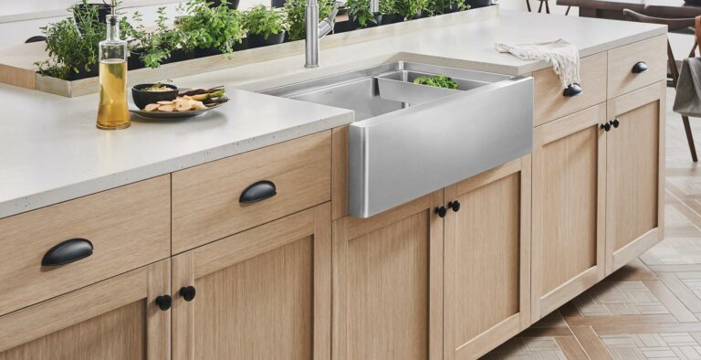 Stainless steel apron-front sink in a light quartz countertop with wood shaker cabinets