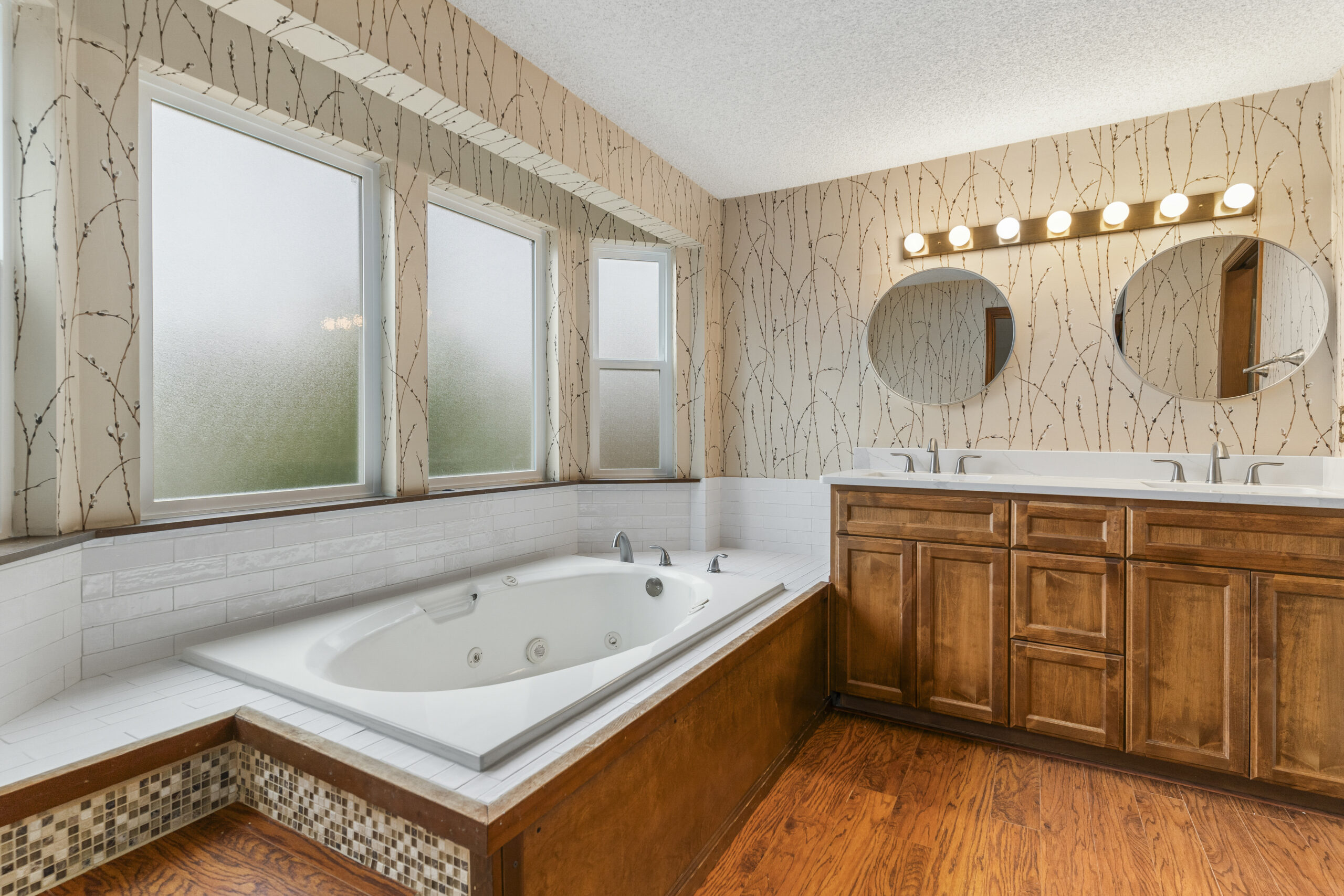 Remodeled bathroom with soaking tub, dual vanity with quartz countertops, wood cabinetry, and modern fixtures in a Washington State home.