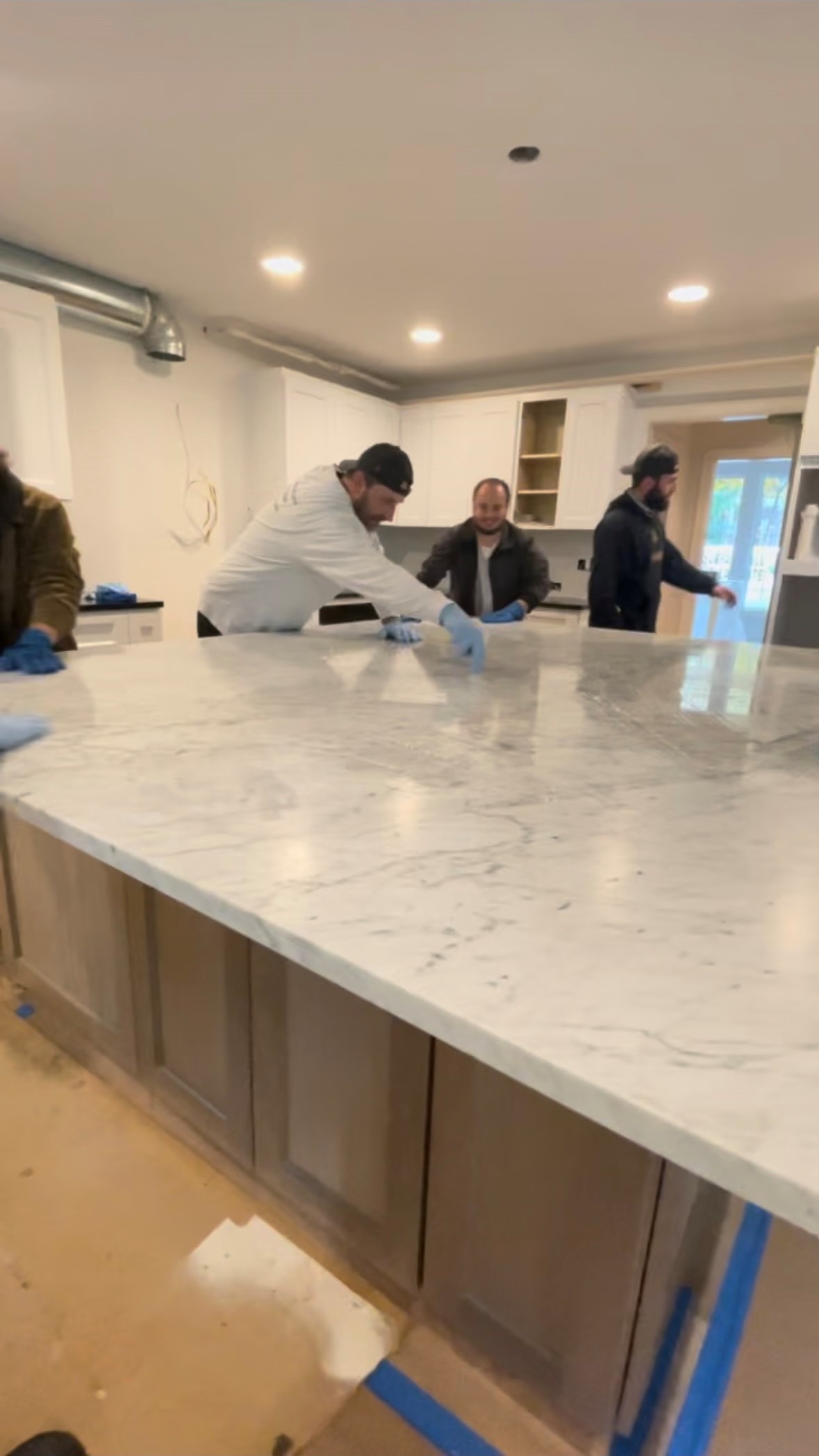Tops Countertops team applying sealant to a newly installed marble kitchen island to protect the surface from stains and moisture.