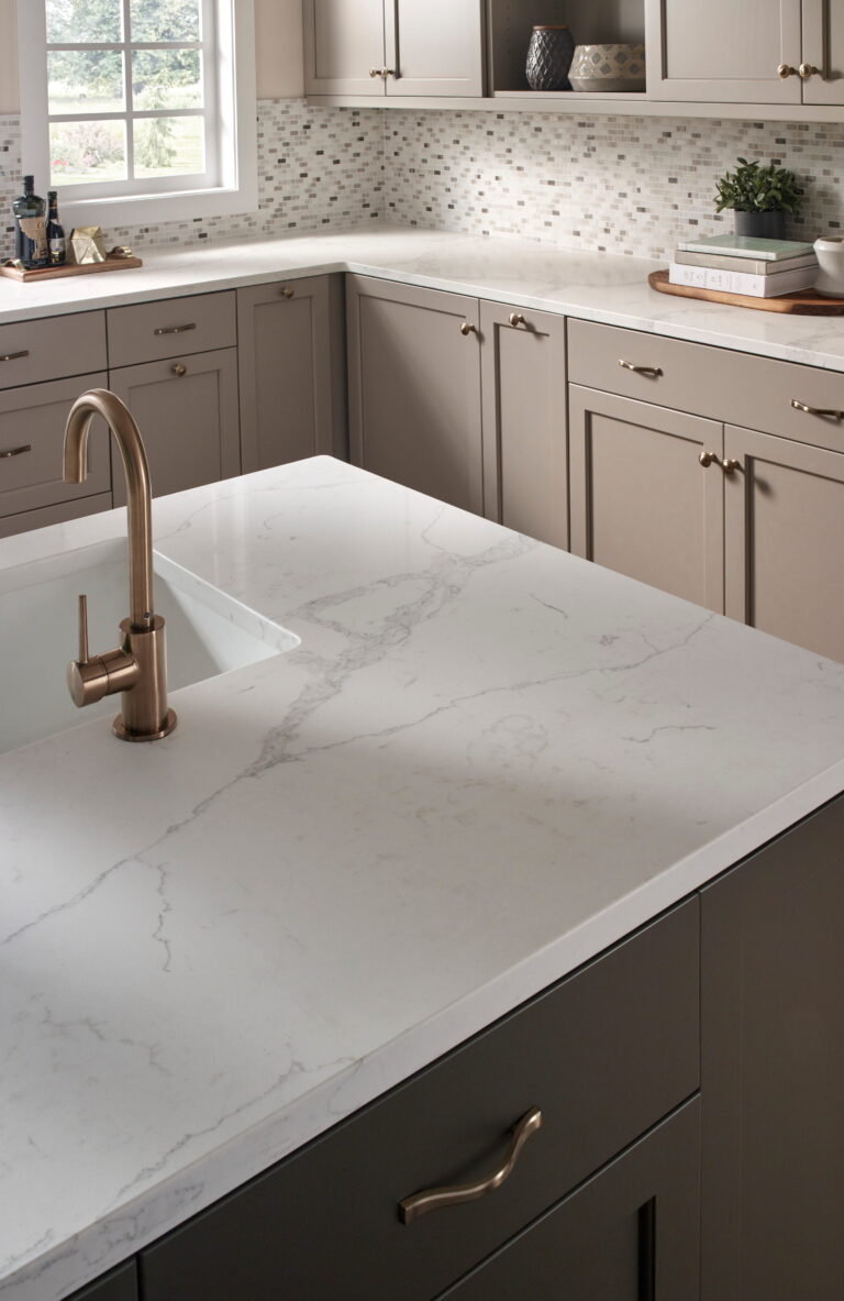 Statuary Classique quartz kitchen island with gray veining, brushed bronze faucet and taupe cabinets