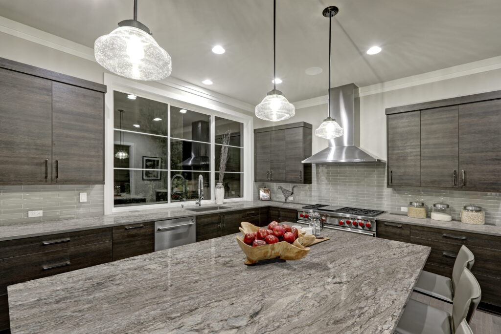 Azul Celeste granite kitchen island with gray and white movement, dark wood cabinets and pendant lights