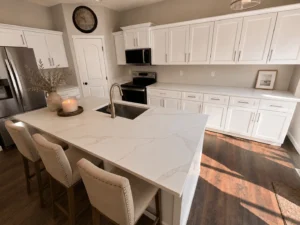 Calacatta Elysio quartz kitchen island with gray and gold veining, undermount sink and white cabinets