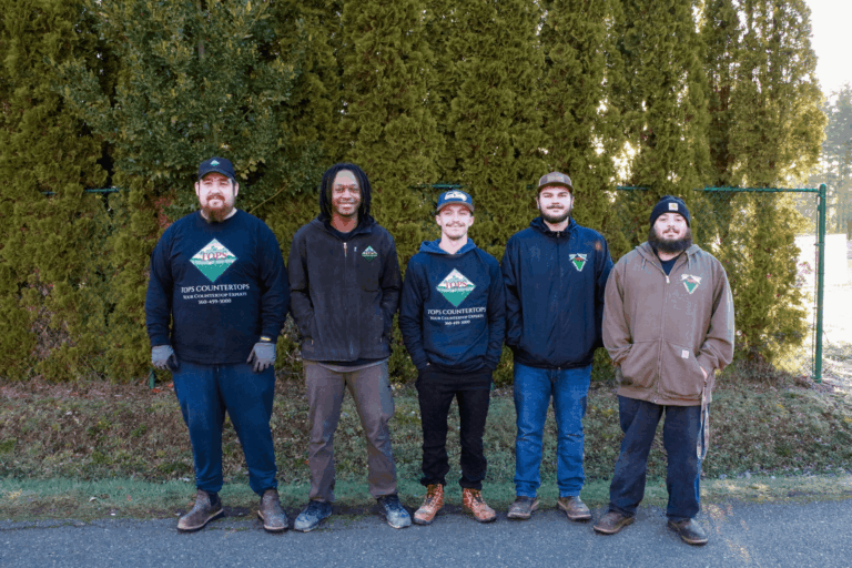 Five members of the Tops Countertops installation team in company sweatshirts standing outdoors