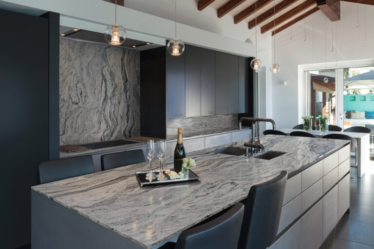 Modern kitchen with a gray and white wave-patterned granite island and full-height granite backsplash