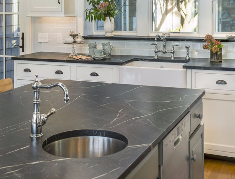 Black Vermont soapstone kitchen island and countertops with white veining, round sink and white cabinets