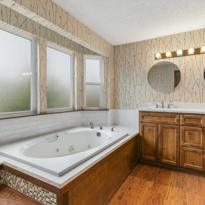 Remodeled bathroom with soaking tub, dual vanity with quartz countertops, wood cabinetry, and modern fixtures in a Washington State home.