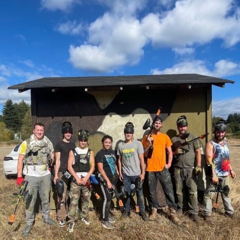Tops Countertops crew in paintball gear posing in front of a field bunker